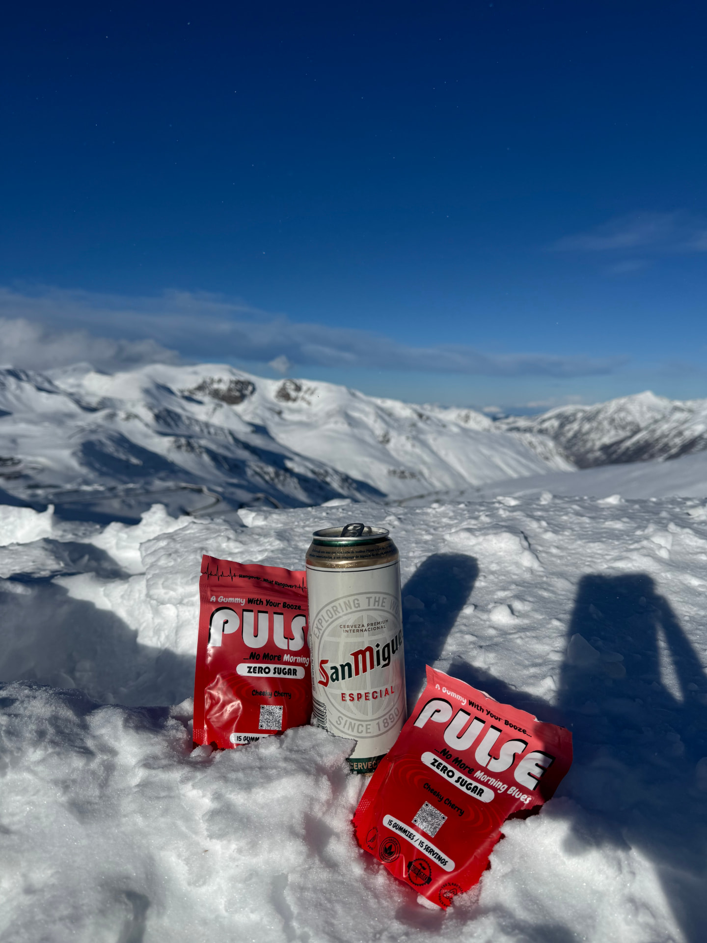 Two PULSE pouches and a drink sitting in snow on a mountain summit
